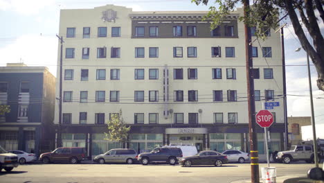 a multi-story building with a 'ford' sign on a city street with parked cars