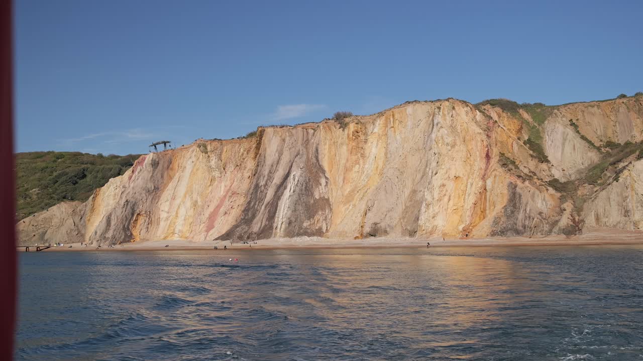 acantilados con vibrantes colores estratificados junto al mar, bajo un cielo azul claro
