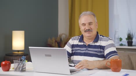 home office worker old man smiles at camera.