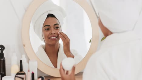 woman applying moisturizer in front of mirror