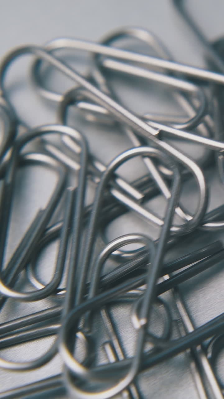 motion over metal paperclips heap for school and office on clean grey surface extreme close view