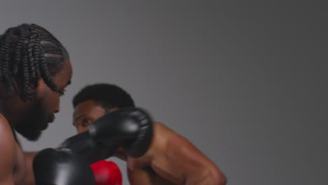 Close-Up-Studio-Shot-Of-Two-Male-Boxers-Wearing-Gloves-Fighting-In-Boxing-Match-Against-Grey-Background-2