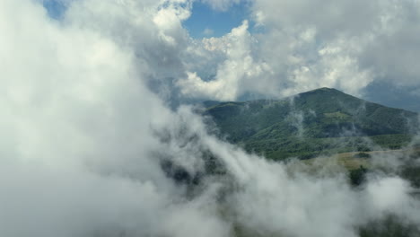 flying trough white fluffy clouds above green mountain peaks