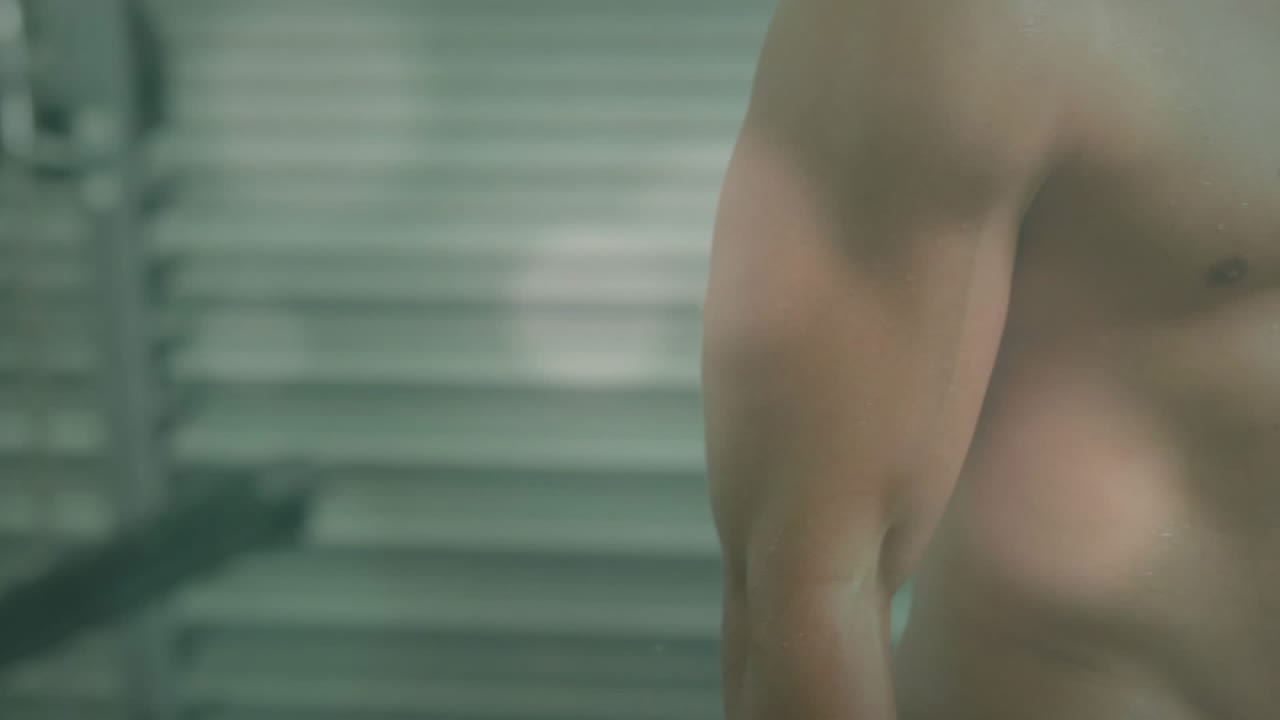 Man gripping hex dumbbell and performing biceps curl in gym, flares highlighting muscles, shutter