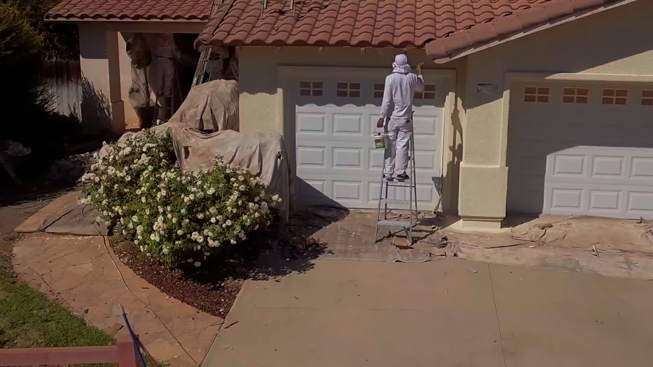 Luftfoto, droneoptagelse af en person der maler ydersiden af et hus i LA's forstæder, i Los Angeles, Californien, USA.