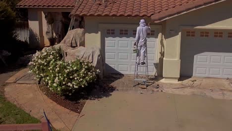 aerial, drone shot, of person working on painting the exterior, of a house, in la suburbs, in los angeles, california, usa