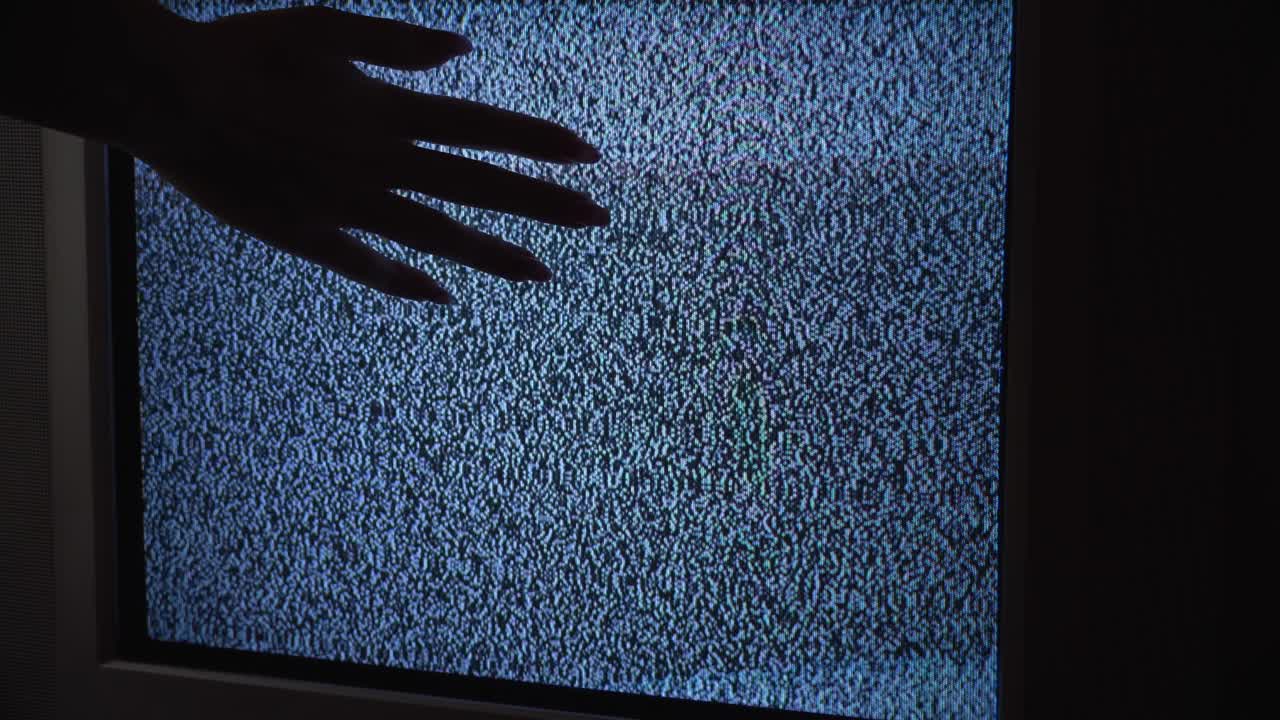 mano femenina tocando una vieja pantalla de tv con ondas