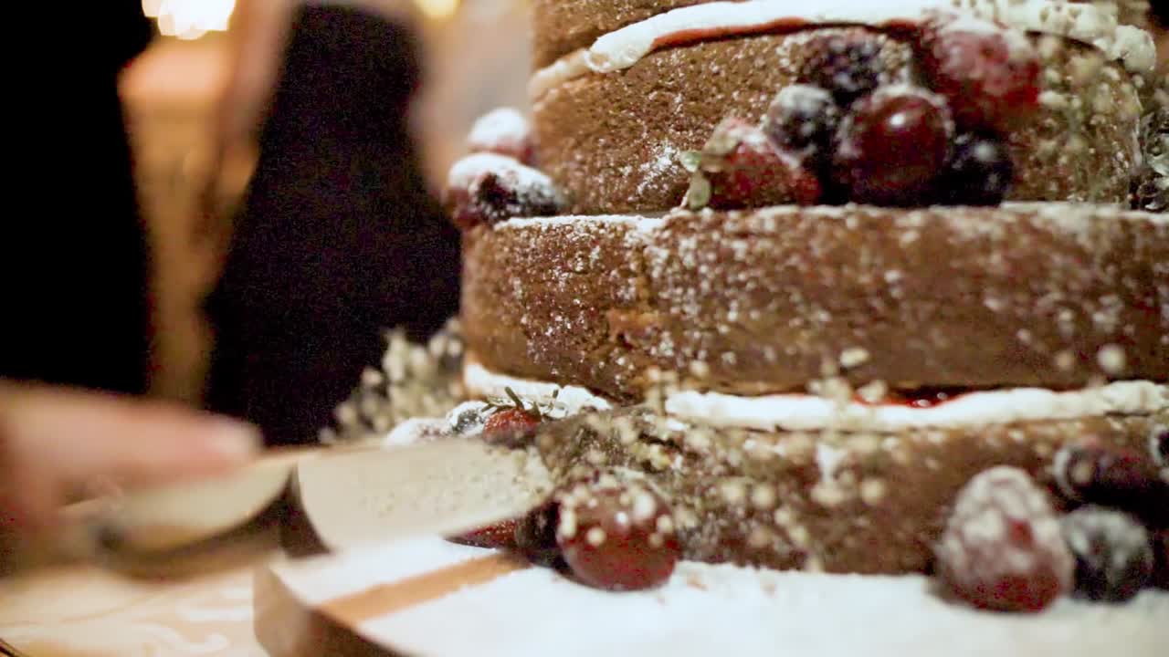 Cutting a delicious cake with berries of a wedding