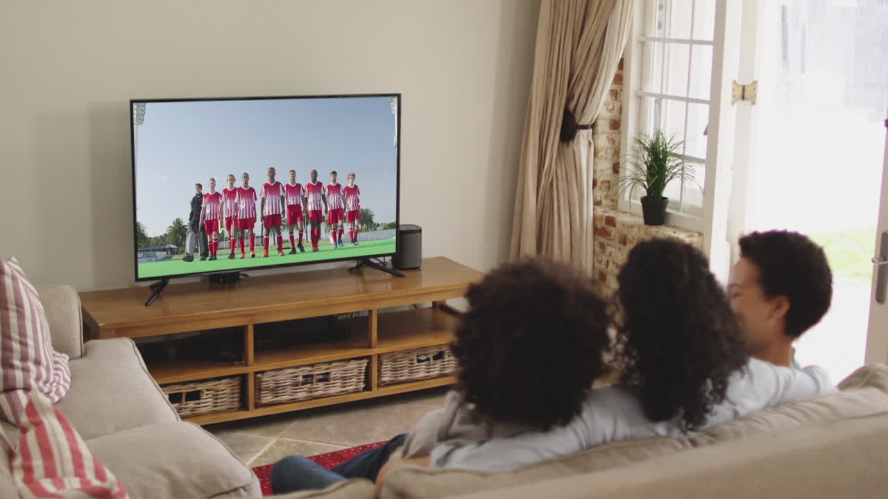 Famiglia felice seduta a casa insieme che guarda un evento sportivo in TV