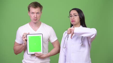 young asian woman doctor with young man patient showing digital tablet