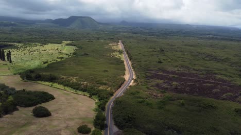 Un-Dron-Cinematográfico-De-4k-Revela-Una-Toma-De-Un-Automóvil-Conduciendo-Por-La-Carretera-En-El-Campo-En-La-Gran-Isla-De-Hawaii