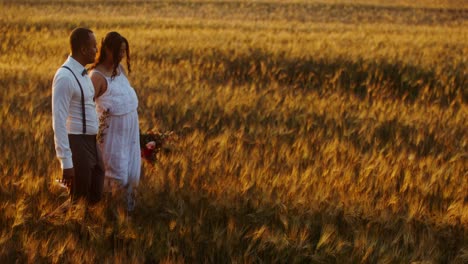 couple walking in a wheat field at sunset