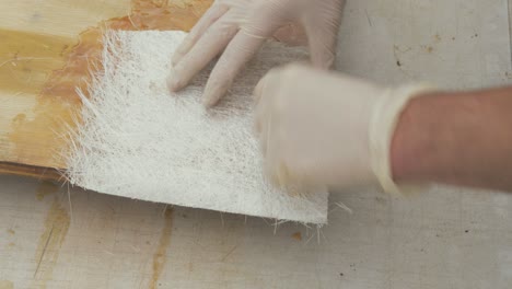 pressing down fiberglass chopped strand mat over plywood