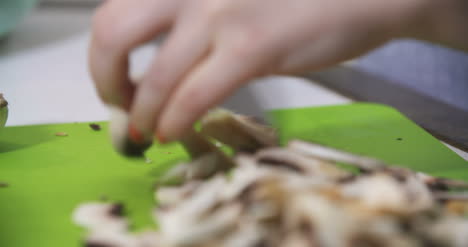 ama de casa cortando champiñones en la cocina para cocinar