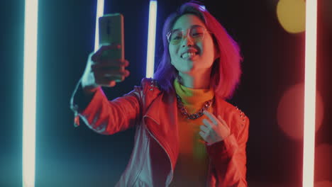 stylish young woman taking a selfie in neon light