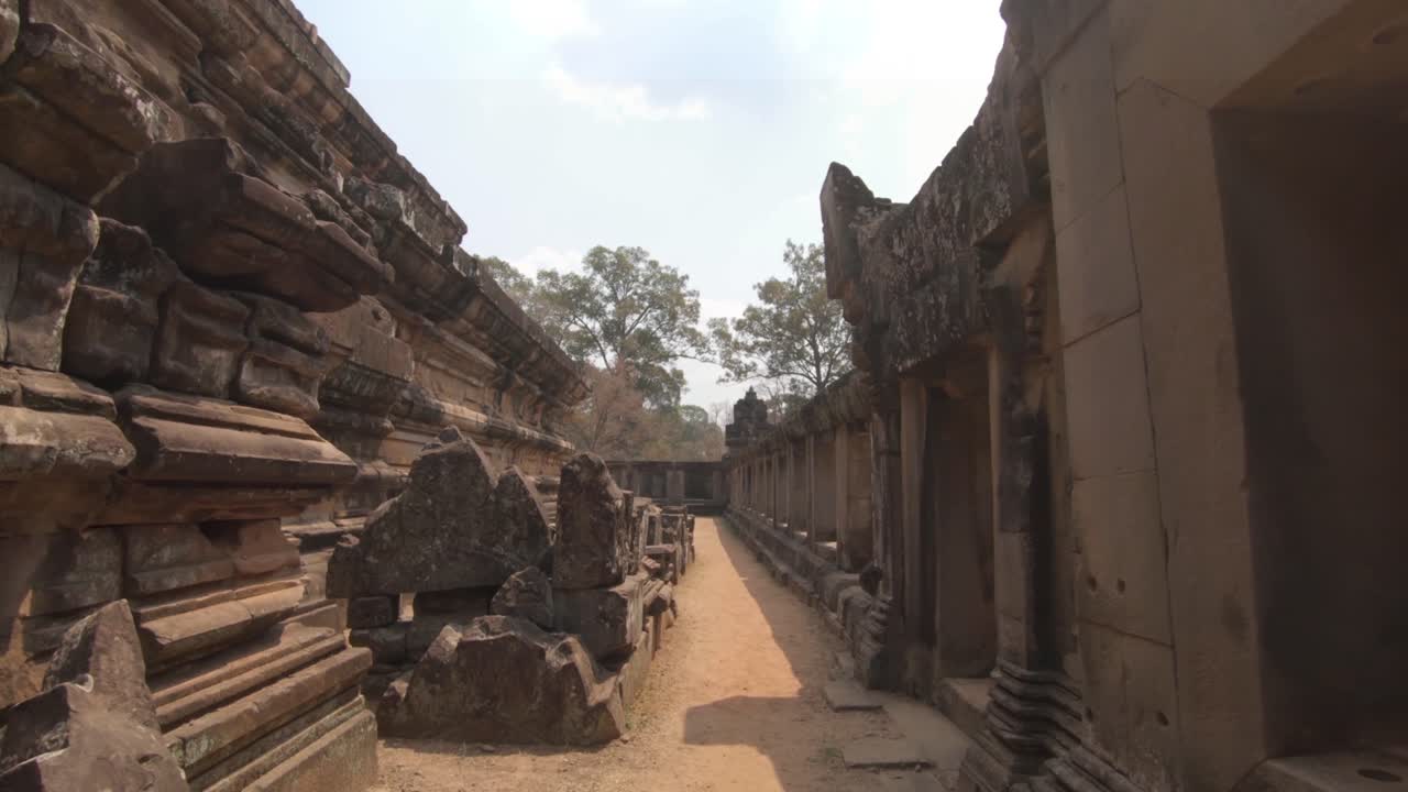 Tourist walking point of view of Angkor temple ruins and carved walls