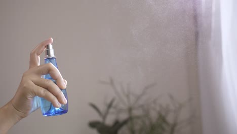 woman using spray air freshener indoors