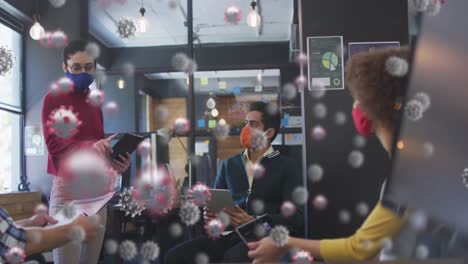 animation of covid 19 cells over colleagues in office wearing face masks
