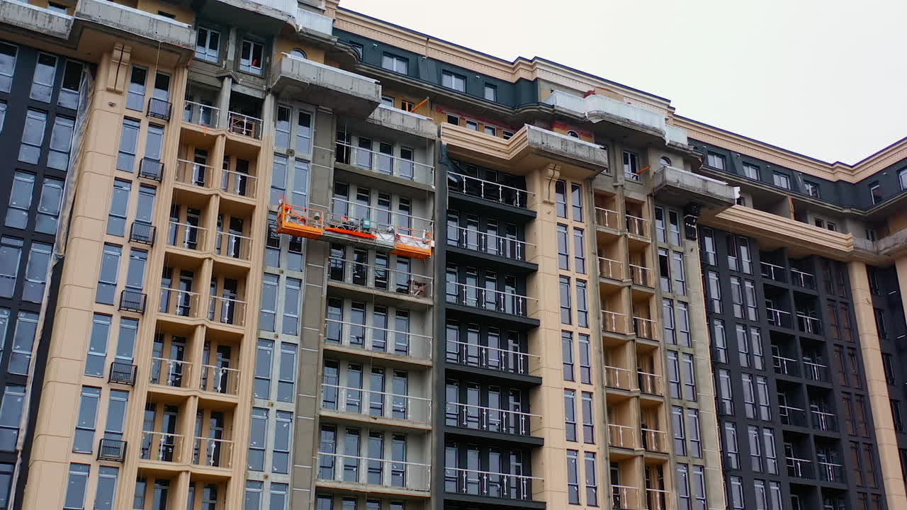 Building of new tower architecture. Modern multi storey building under construction. Front view of a high-rise building. Workers build the tall house.