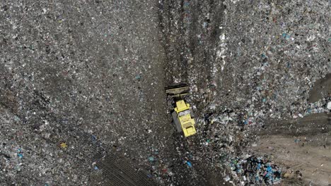 bulldozer retrocediendo en un vertedero de basura