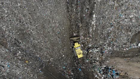 bulldozer backing up in a garbage landfill