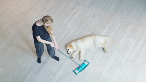 teenager mopping floor with dog