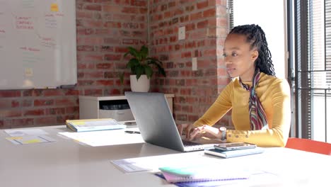 Mujer-De-Negocios-Informal-Afroamericana-Usando-Una-Computadora-Portátil-En-Una-Oficina-Soleada