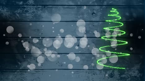 Animation-of-glowing-green-Christmas-tree-and-white-spots-on-blue-wooden-rustic-background.-Christma