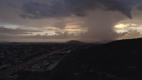 toma aérea bastante estacionaria de una carretera que conduce a una colina con nubes pesadas en el horizonte