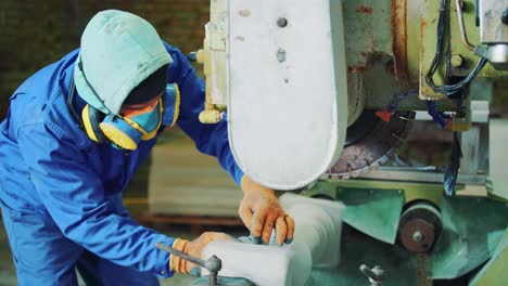 at the factory, a male worker in a protective mask and gloves processes a decorative stone on a machine. craft of marble, sandstone