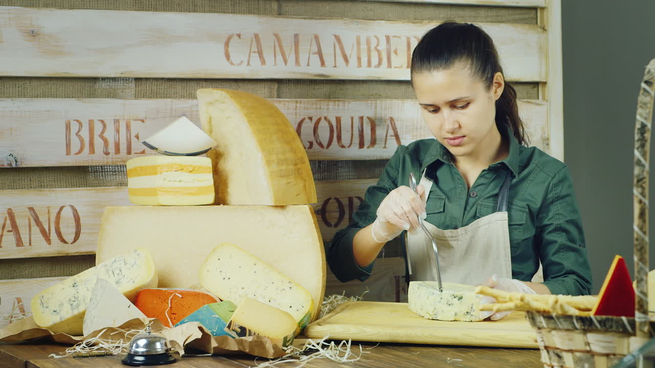 el vendedor trabaja en una tienda de quesos: el queso cortado con un cuchillo especial hecho de alambre cercano es grande