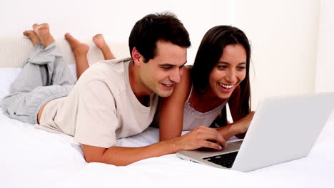 una pareja encantada usando una computadora portátil