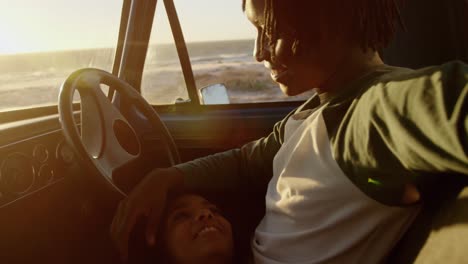 Front-view-of-African-american-woman-lying-on-mans-lap-in-a-pickup-truck-at-beach-4k