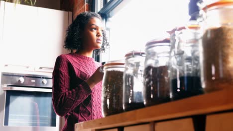 Woman-holding-a-coffee-mug-near-the-window