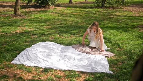 a lady is preparing a picnic blanket and dressing it up for a family picnic