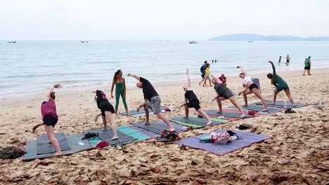 group practicing yoga on a sandy beach