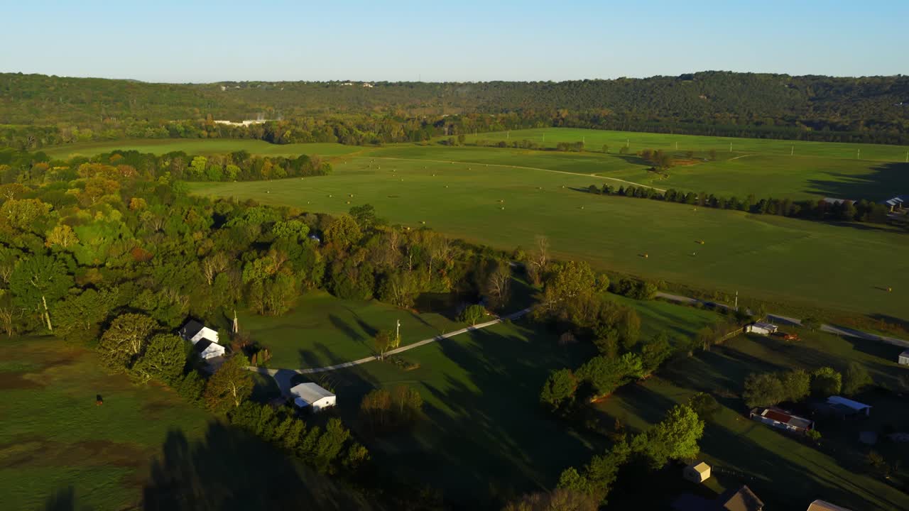 Tierras de cultivo rurales con balas de heno cerca de casas de campo que muestran una vida agrícola tranquila, inclinación aérea hacia arriba y descenso, Fayetteville, Arkansas, EE. UU.