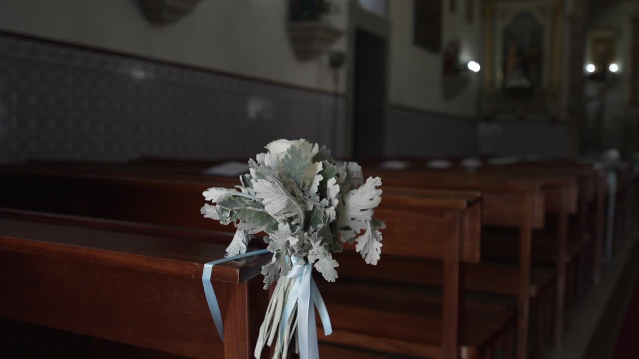 Elegant floral wedding arrangement tied to a church pew