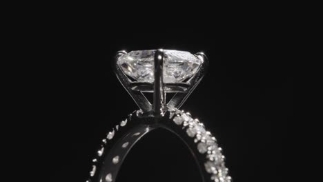 primer plano, anillo de diamantes girando lentamente contra el fondo negro del estudio