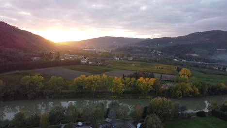 Slowly-orbiting-Aerial-overview-of-Tuscany-province,-Italian-countryside-green-vineyard-covered-hills-sunset-on-a-cloudy-day