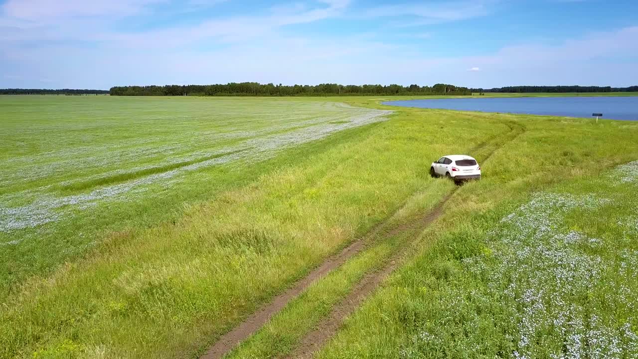 car turns back on grass from lake among fields
