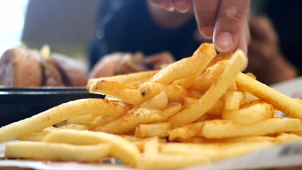 Close-Up of Hand Picking Up Seasoned French Fry