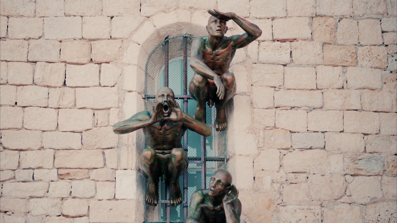 Antibes, France - October 1, 2024: Bronze sculpture by Nicolas Lavarenne of man on the window of a building