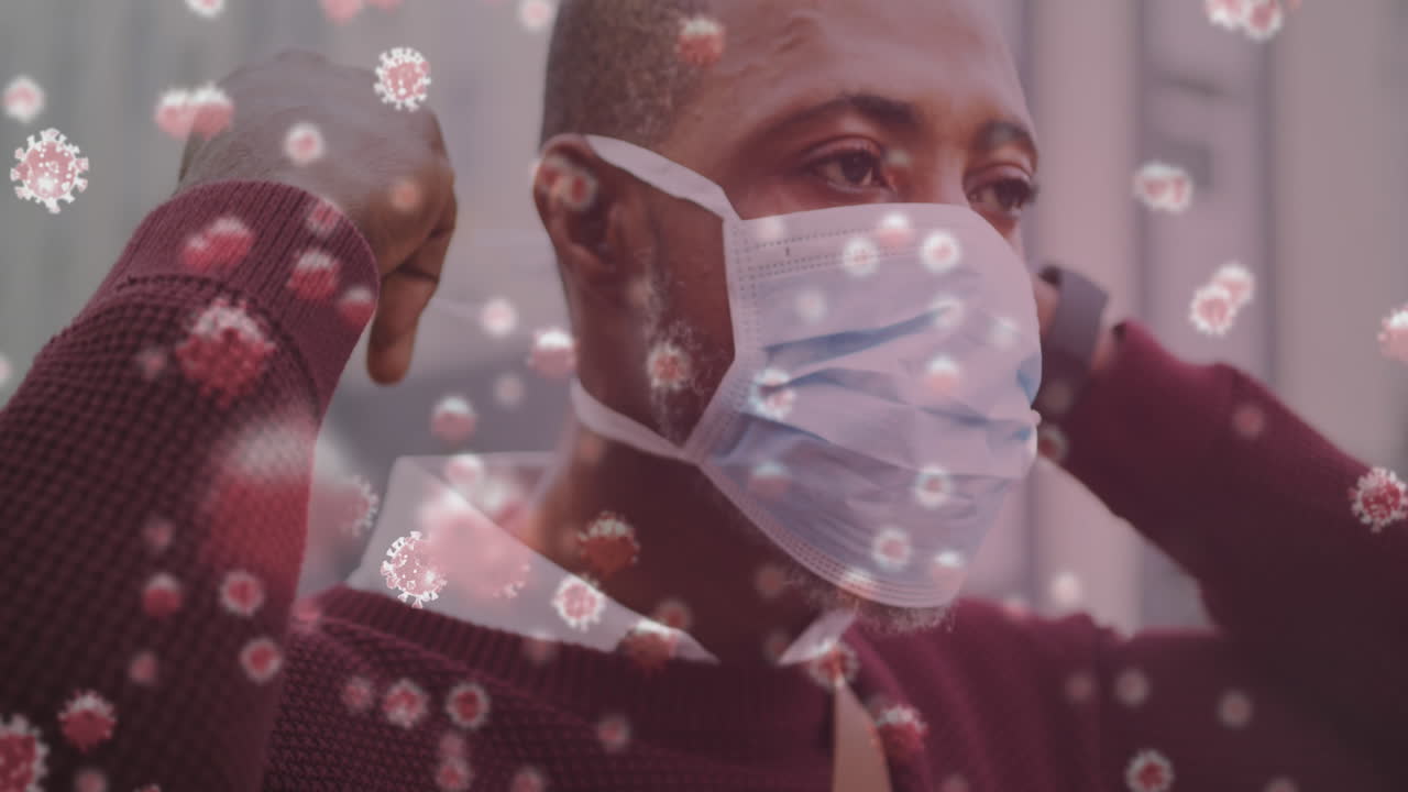 múltiples células de covid-19 flotando contra un hombre afroamericano que usa una máscara facial