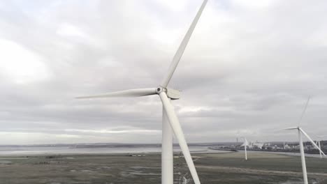 sustainable electrical wind turbines spinning on england farmland skyline orbit left aerial view