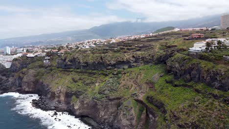 vista aérea de drones de una costa empinada épica con pueblos y casas junto a la caída en el norte de tenerife, islas canarias, españa