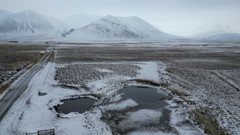 Iceland-Landscape-with-One-Road-leading-to-Snowy-Mountains,-Aerial