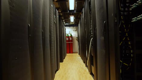 slow pull back through rows of large computer serve towers in a server room of a large business