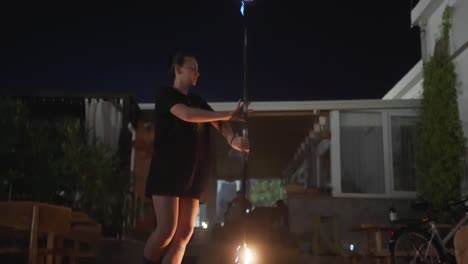 female fire dancer and performer spinning burning torch at night, slow motion