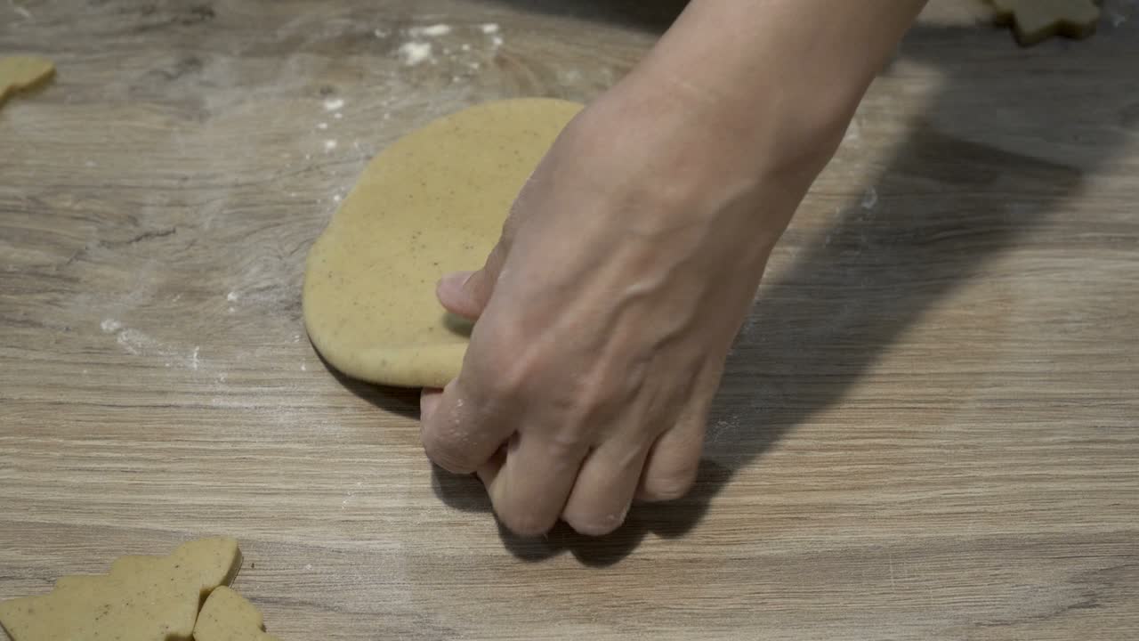 las manos de las mujeres despliegan un pedazo de masa amarilla redonda con un rodillo en la cocina, en una mesa de madera. el concepto de cocinar en casa. primer plano. la vista desde arriba. sin rostro. 4k.